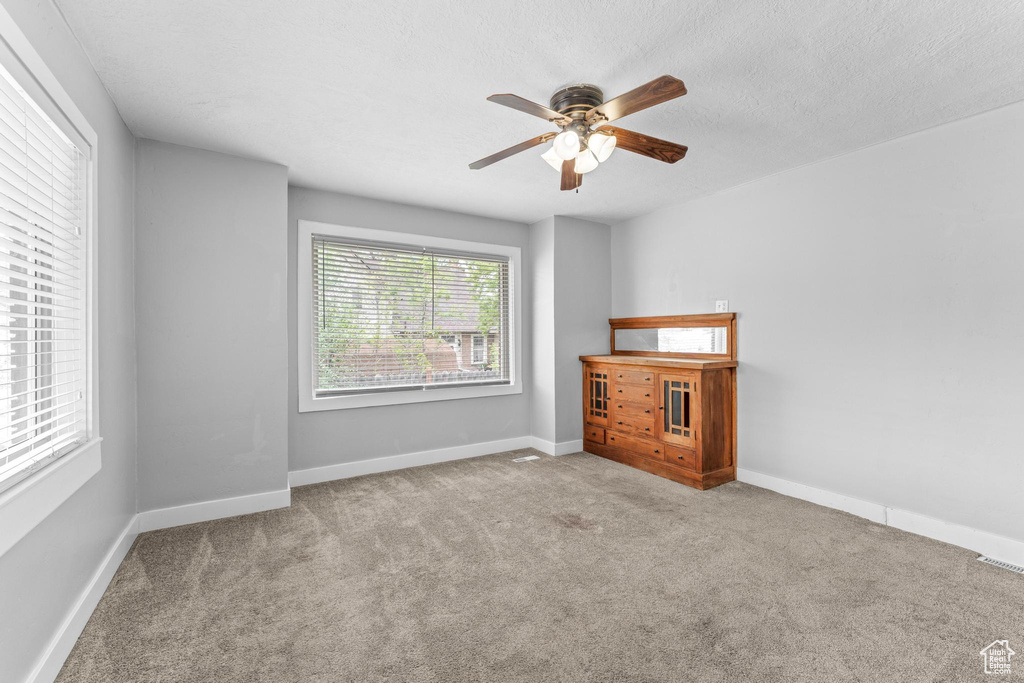 Spare room featuring a ceiling fan, carpet, and baseboards