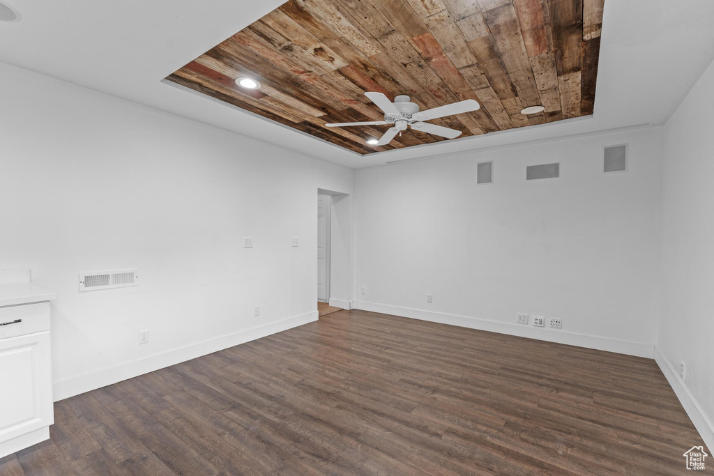 Unfurnished room featuring wooden ceiling, ceiling fan, dark wood-type flooring, and baseboards