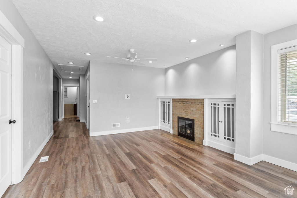 Unfurnished living room with attic access, a ceiling fan, a textured ceiling, wood finished floors, and baseboards