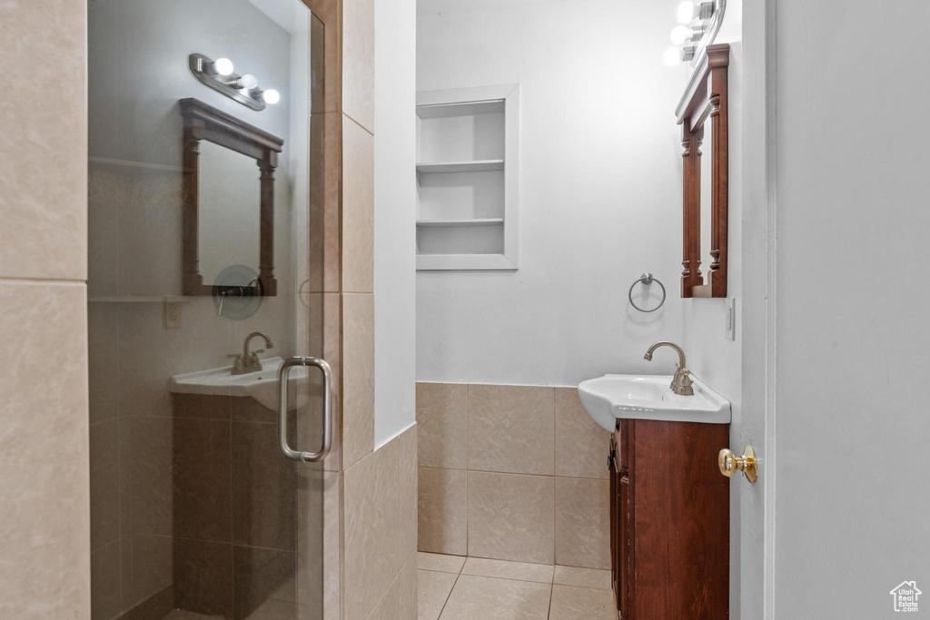 Bathroom featuring a stall shower, tile walls, tile patterned floors, vanity, and built in features
