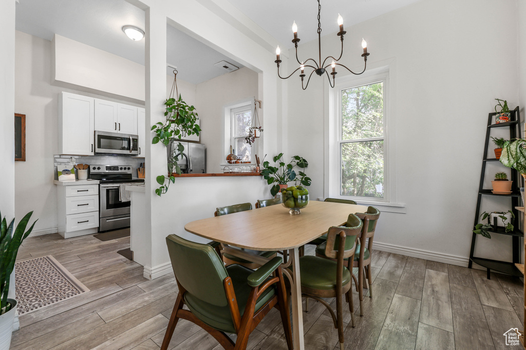 Dining room featuring light wood finished floors, a notable chandelier, and baseboards