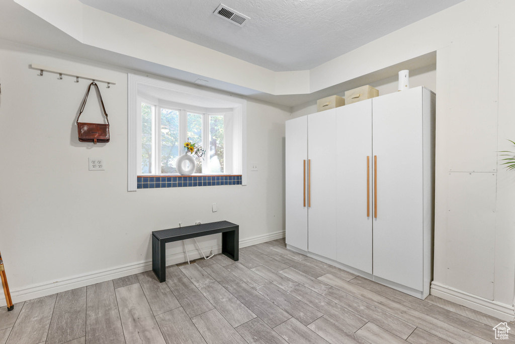 Unfurnished bedroom featuring light wood-style floors, visible vents, baseboards, and a textured ceiling