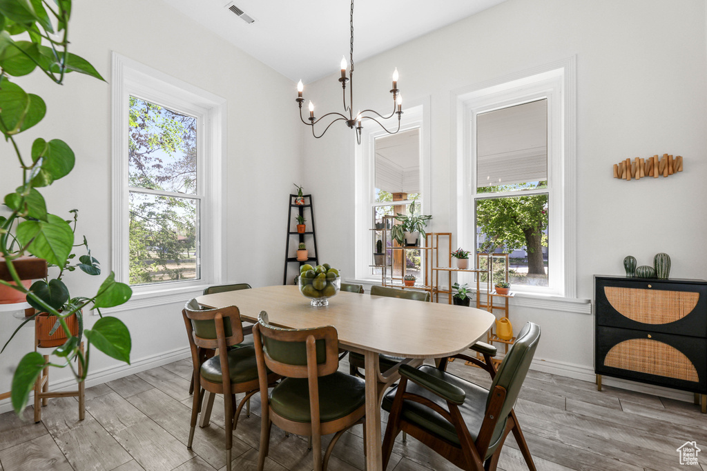 Dining area featuring a chandelier, light wood-style flooring, a healthy amount of sunlight, and visible vents