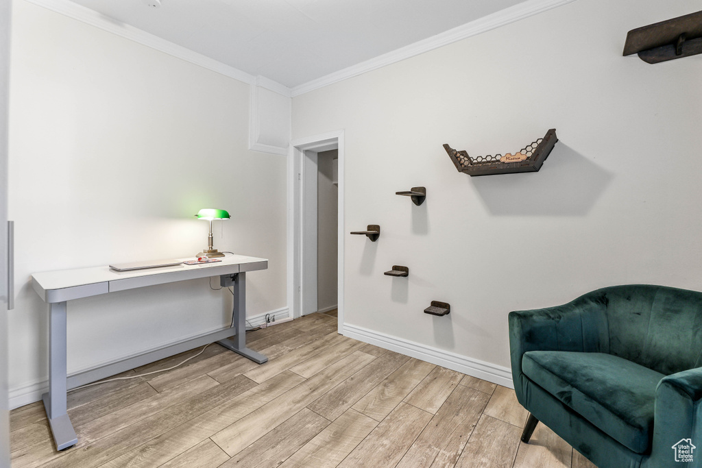 Living area featuring light wood finished floors, baseboards, and ornamental molding