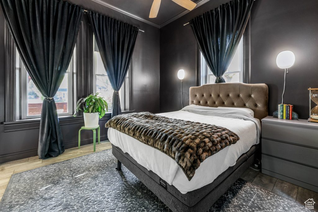 Bedroom with a ceiling fan, ornamental molding, and wood finished floors
