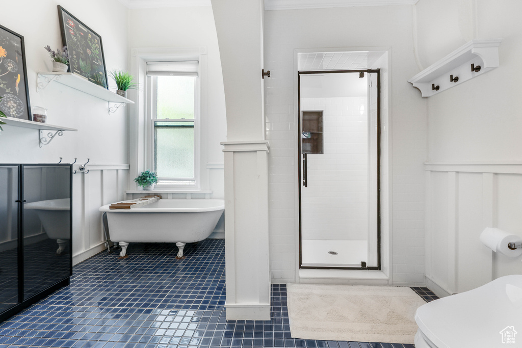 Bathroom with a decorative wall, a stall shower, tile patterned flooring, wainscoting, and a freestanding bath