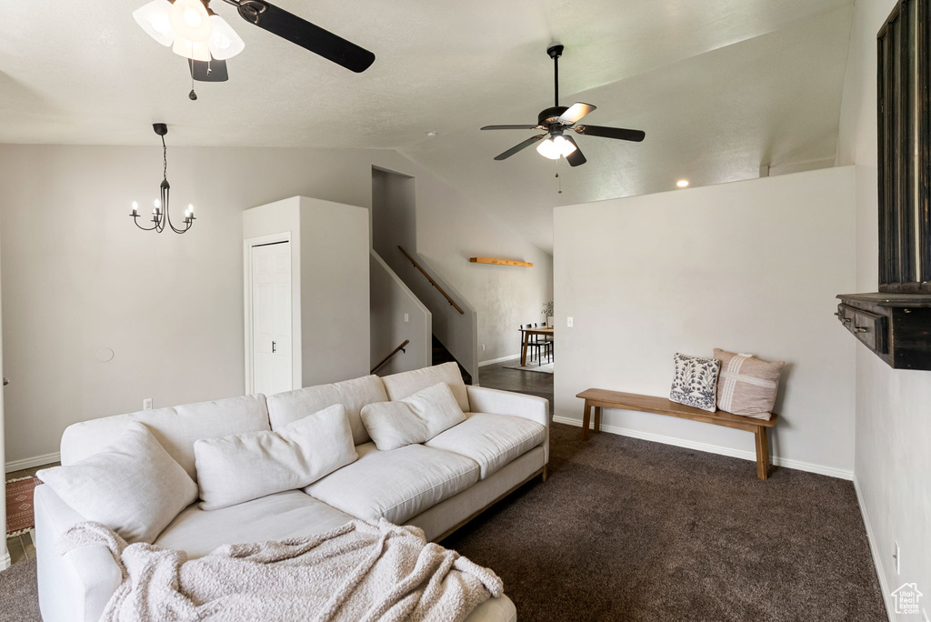 Living room featuring a ceiling fan, vaulted ceiling, baseboards, carpet floors, and a chandelier