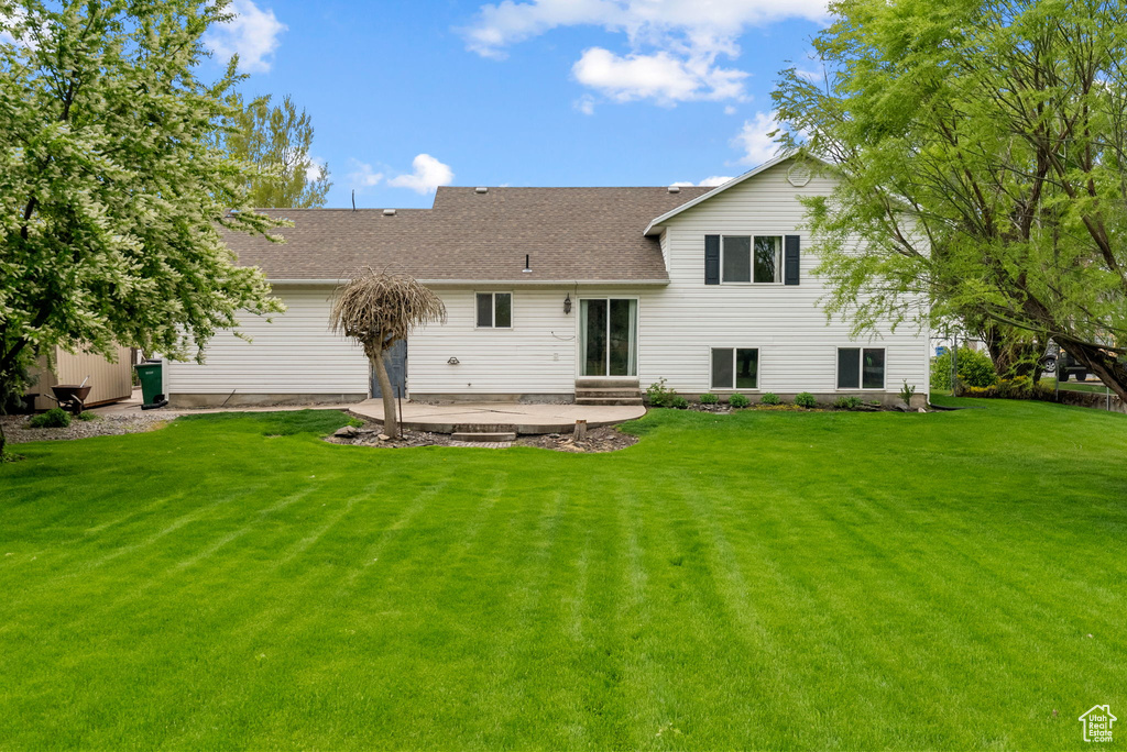 Back of property featuring a patio area, a yard, and a shingled roof