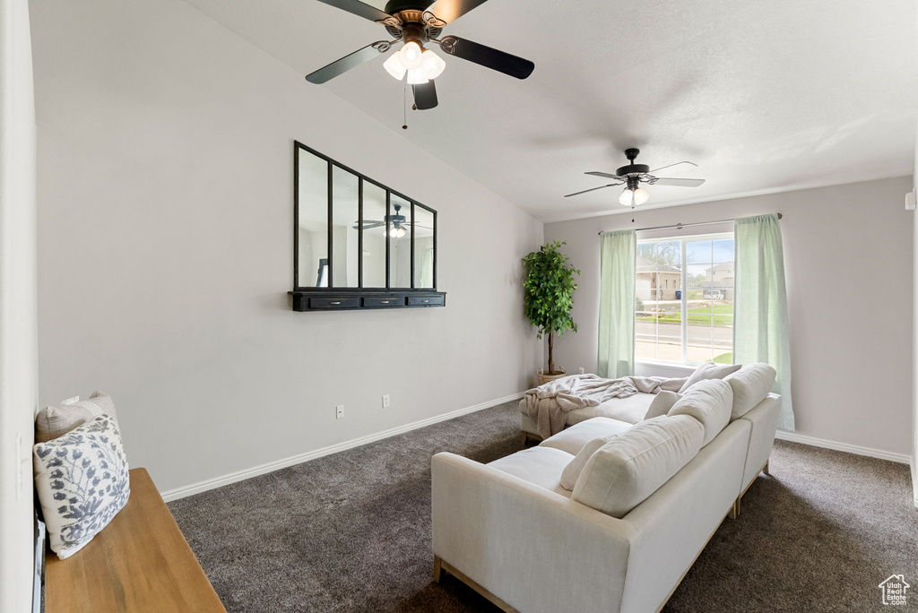 Carpeted living room featuring ceiling fan and baseboards