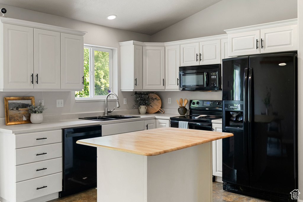 Kitchen featuring black appliances, a sink, white cabinets, vaulted ceiling, and a kitchen island
