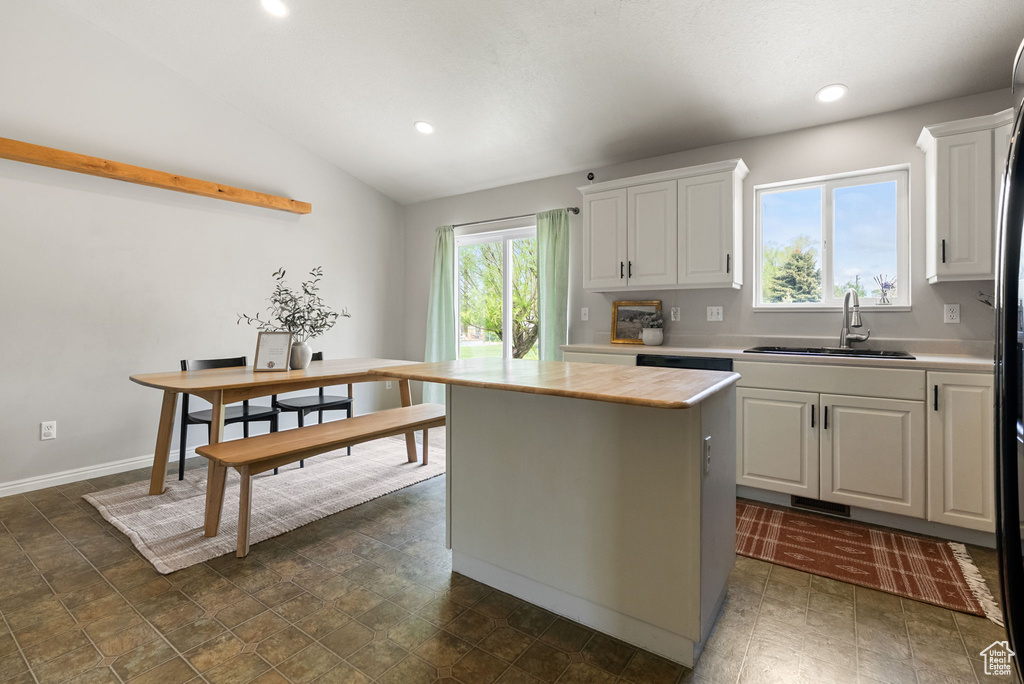 Kitchen featuring a sink, light countertops, white cabinetry, recessed lighting, and vaulted ceiling