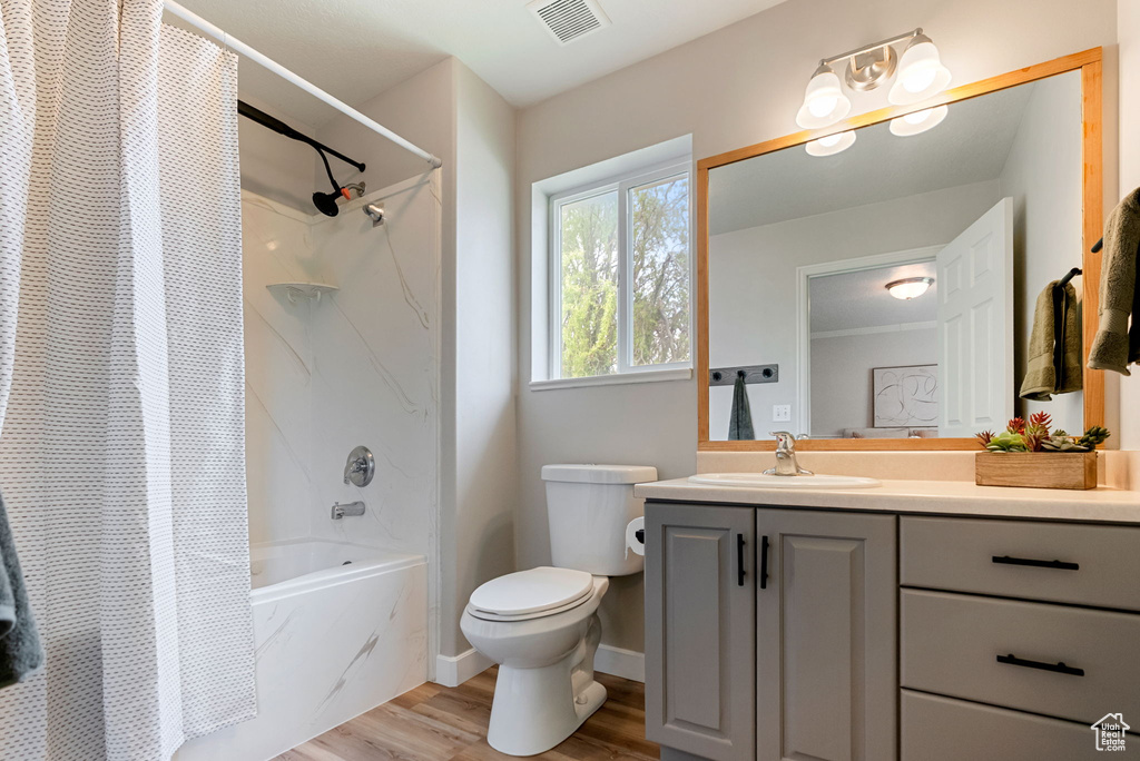 Bathroom featuring shower / bath combination with curtain, vanity, toilet, and wood finished floors