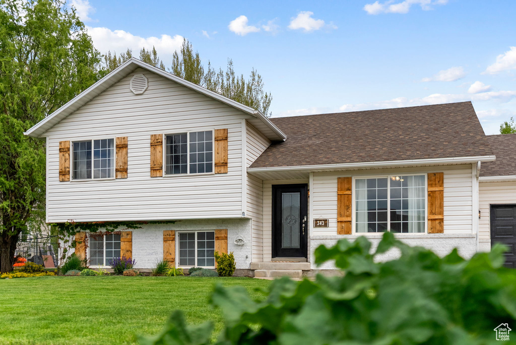 Split level home with a front yard and roof with shingles