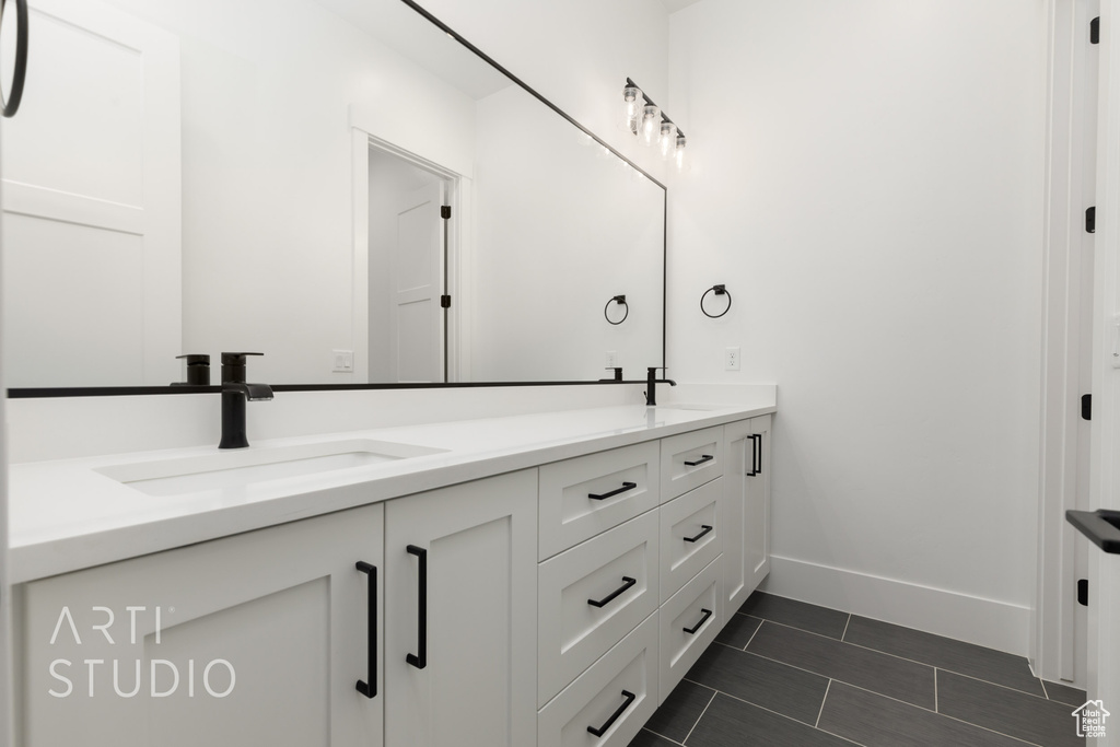Bathroom featuring baseboards, double vanity, and tile patterned floors