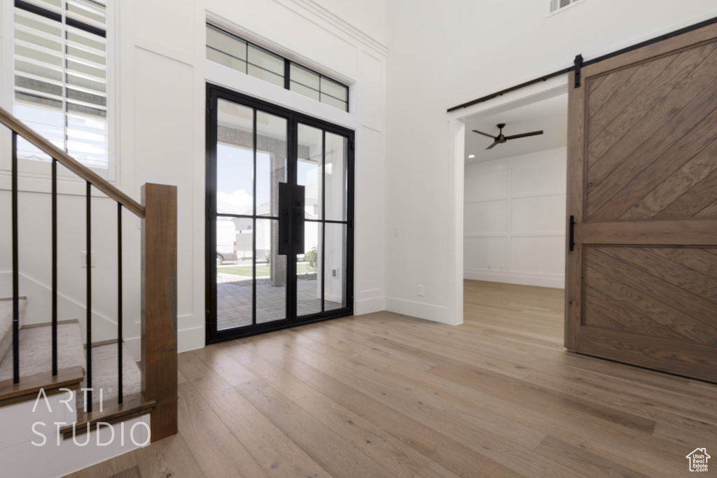 Entryway featuring wood finished floors, a ceiling fan, baseboards, and a barn door