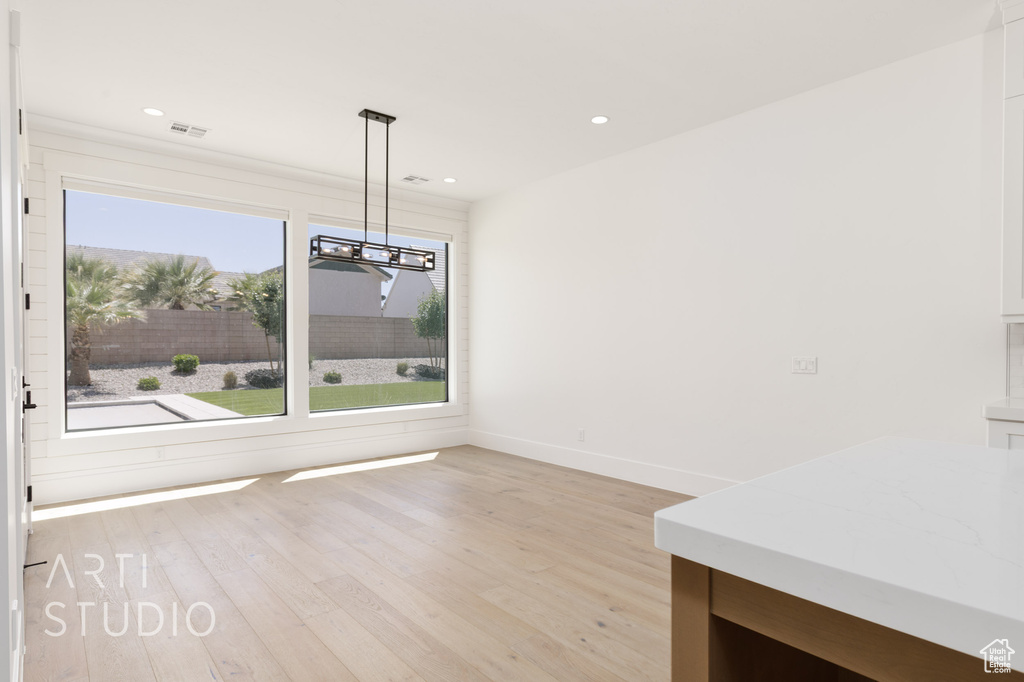 Unfurnished dining area with a chandelier, light wood-type flooring, baseboards, and recessed lighting