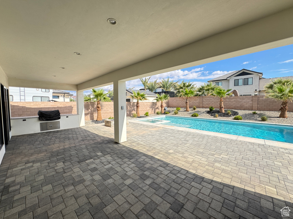 View of pool with a patio area, exterior kitchen, and a fenced backyard