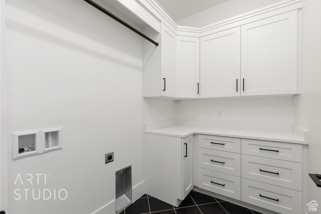 Laundry room with cabinet space, electric dryer hookup, dark tile patterned floors, and washer hookup