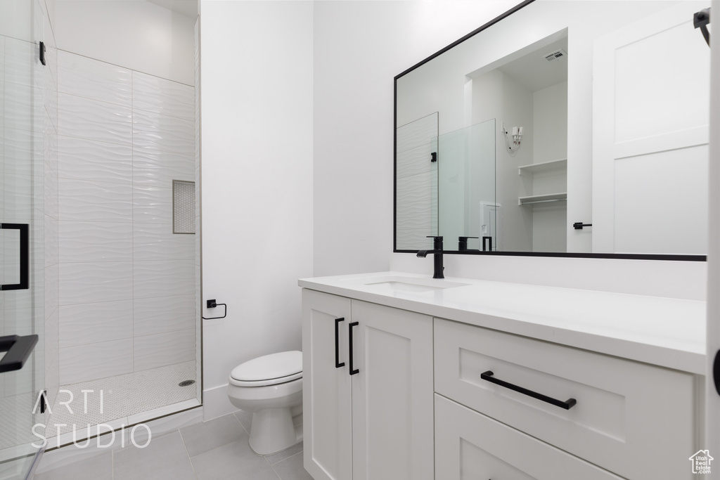 Full bathroom with toilet, a stall shower, vanity, and tile patterned flooring