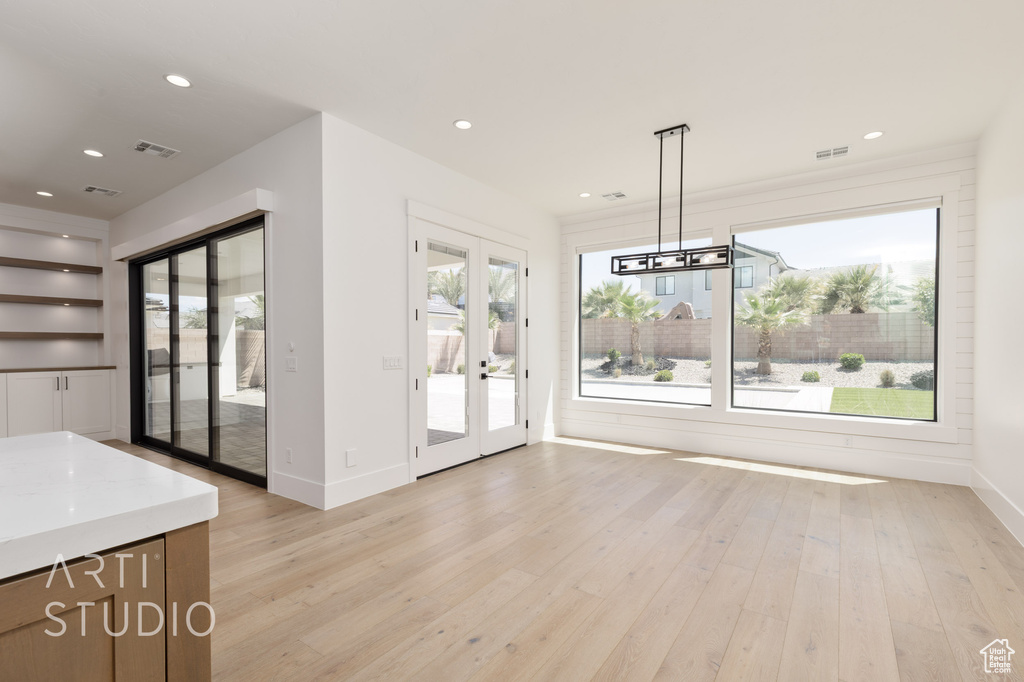 Unfurnished dining area with french doors, baseboards, light wood-style floors, recessed lighting, and built in features