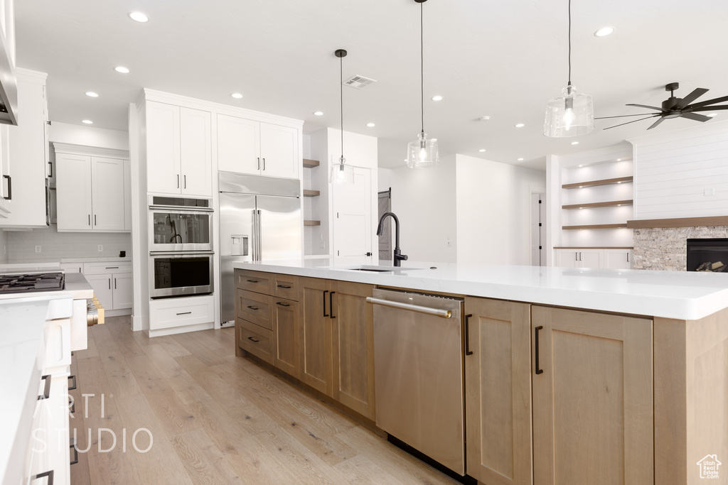 Kitchen with appliances with stainless steel finishes, a ceiling fan, recessed lighting, light wood-style flooring, and open shelves