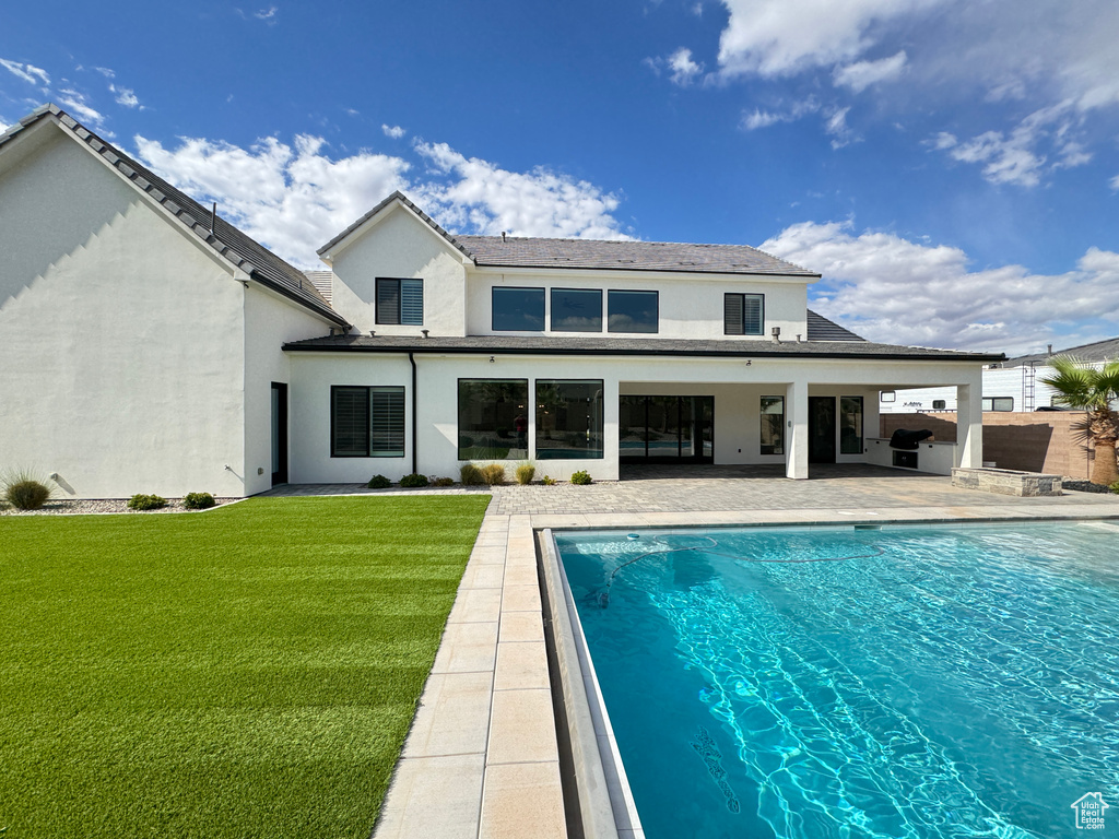 Back of house with a patio, stucco siding, a yard, and an outdoor pool