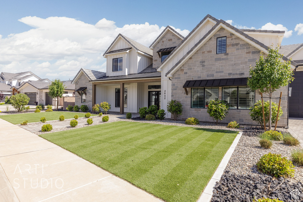 View of front of home featuring board and batten siding, a front lawn, a standing seam roof, and metal roof