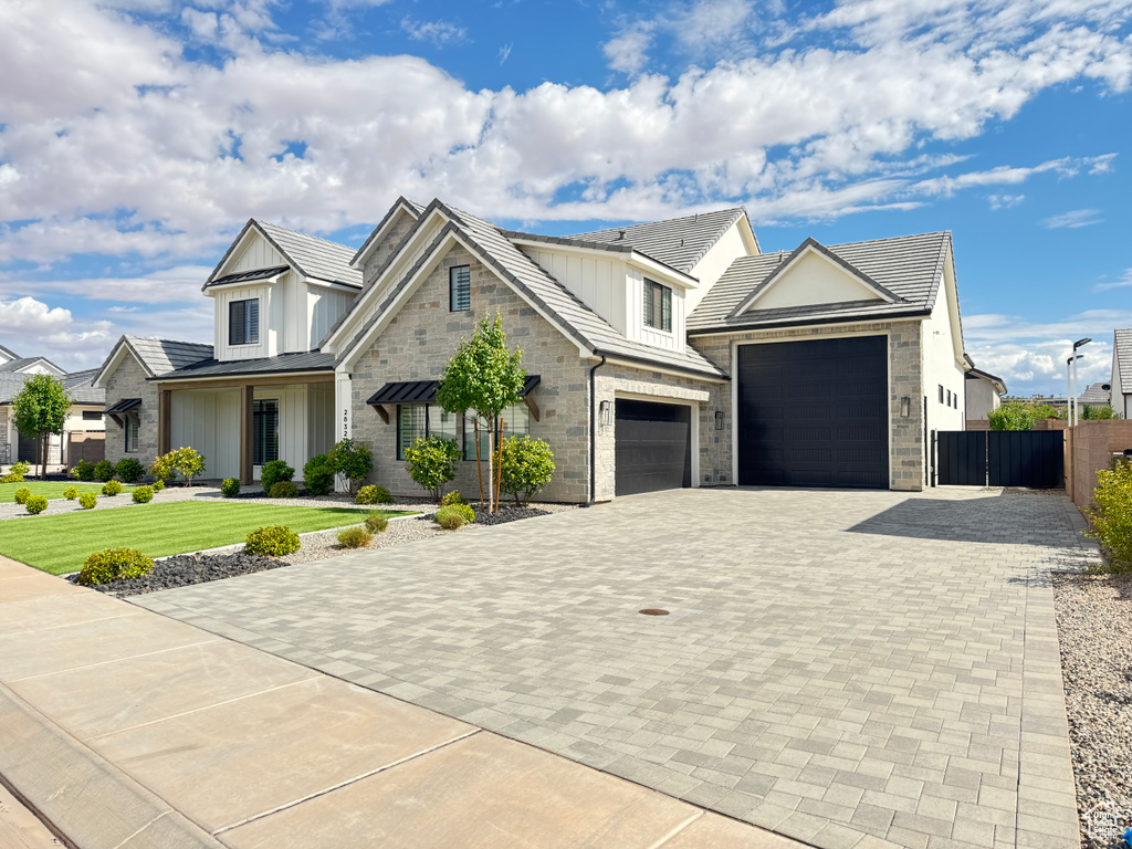 View of front of house with decorative driveway, board and batten siding, and an attached garage