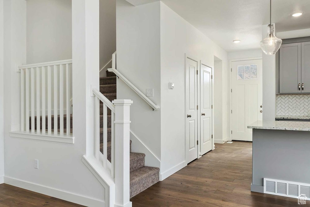 Foyer entrance featuring dark wood-type flooring, stairway, baseboards, and recessed lighting