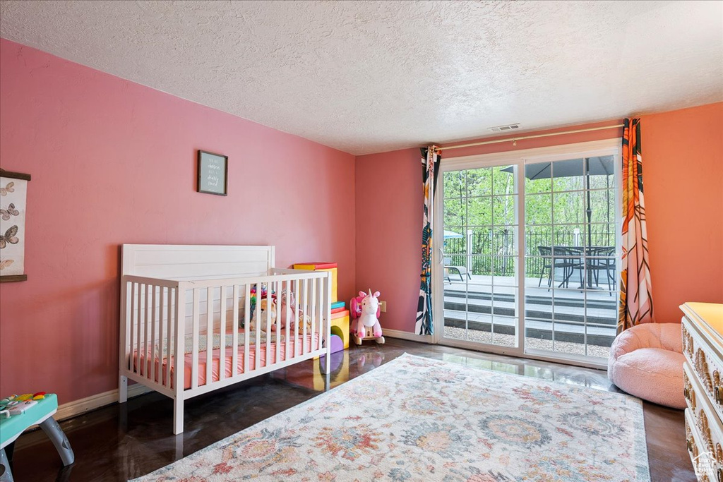 Bedroom with wood finished floors, a textured ceiling, baseboards, and access to outside