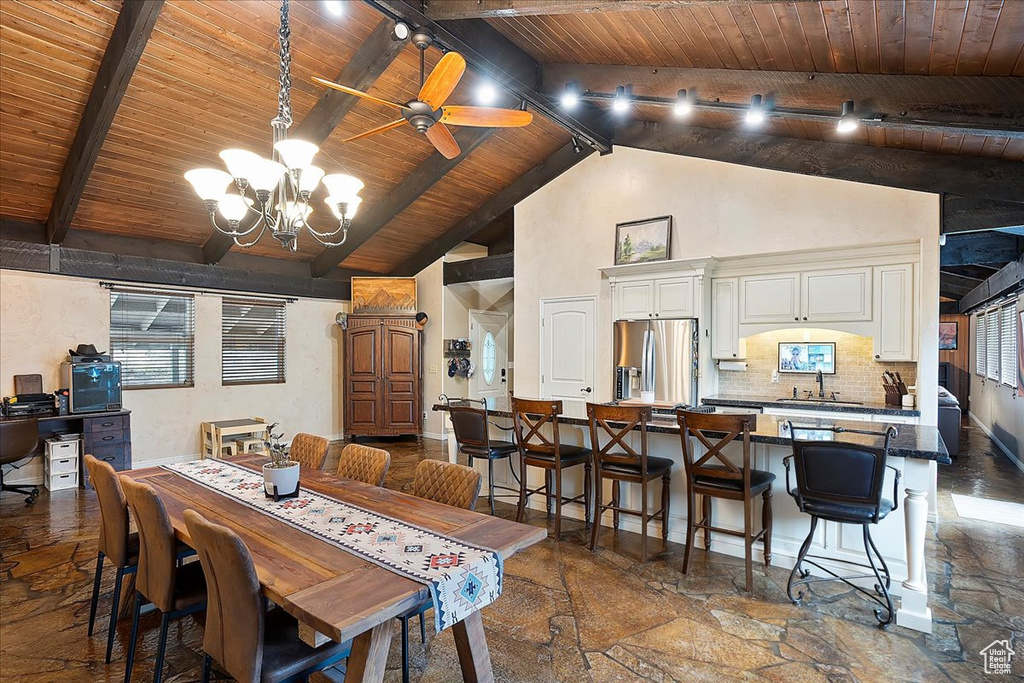 Dining area with wooden ceiling, stone tile flooring, a chandelier, beam ceiling, and a ceiling fan