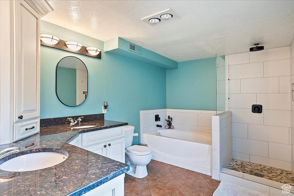 Full bathroom featuring a textured ceiling, a bath, vanity, toilet, and tiled shower