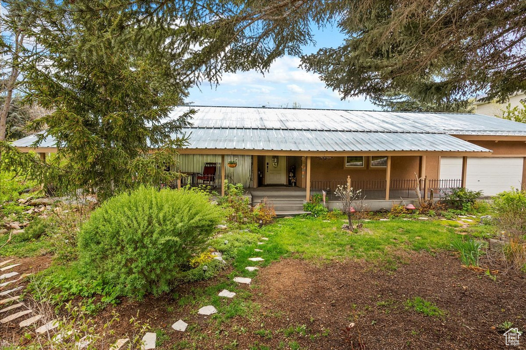 View of front of home with covered porch, metal roof, and an attached garage