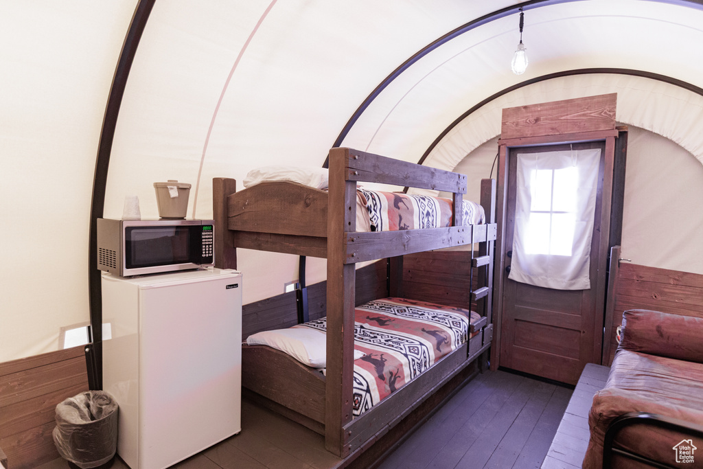 Bedroom featuring fridge and wood-type flooring
