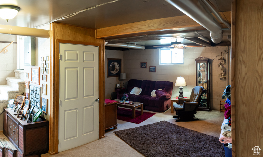 Living area featuring light colored carpet, ceiling fan, and stairs
