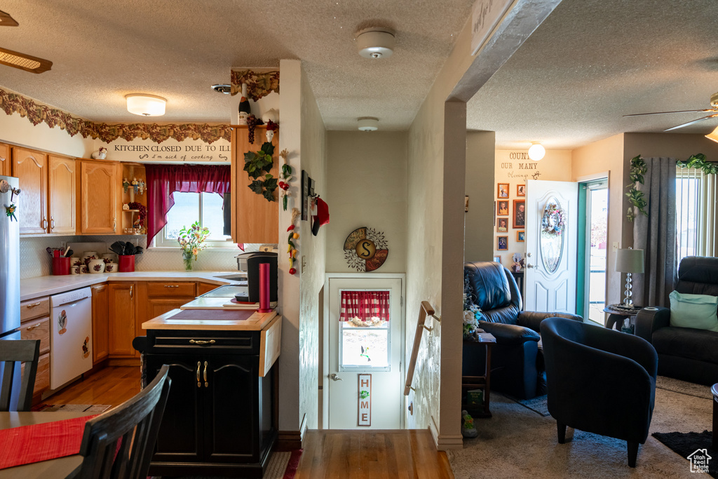 Kitchen featuring white dishwasher, a textured ceiling, ceiling fan, light countertops, and open floor plan