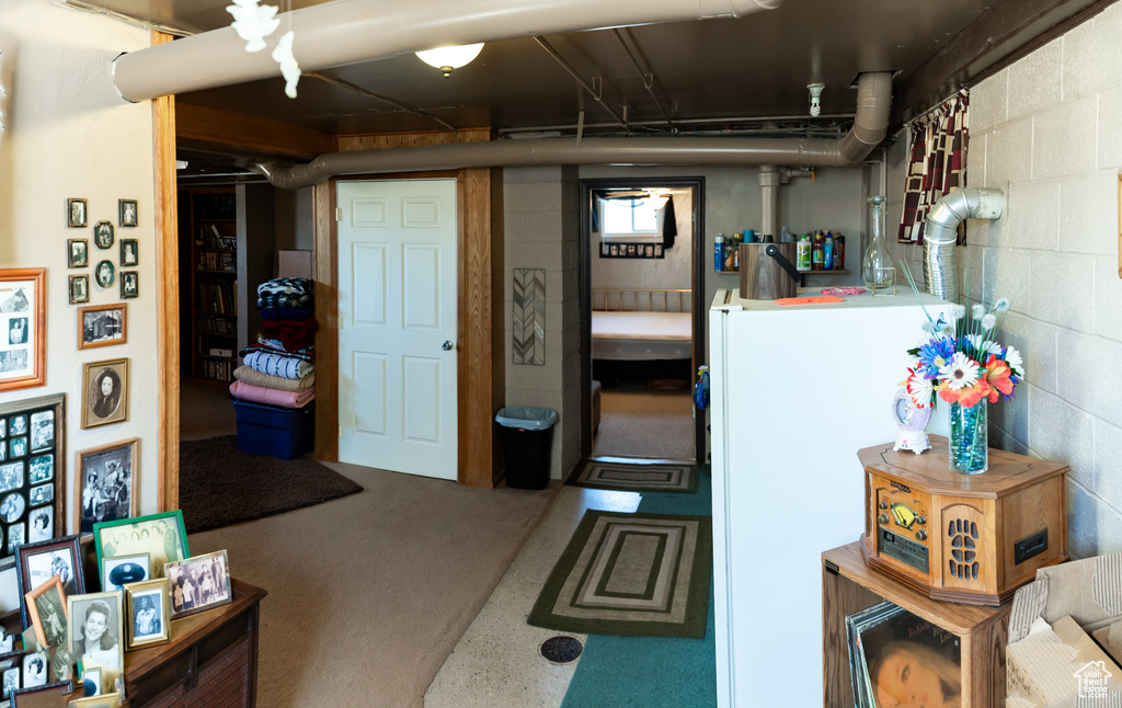 Basement featuring concrete block wall and freestanding refrigerator