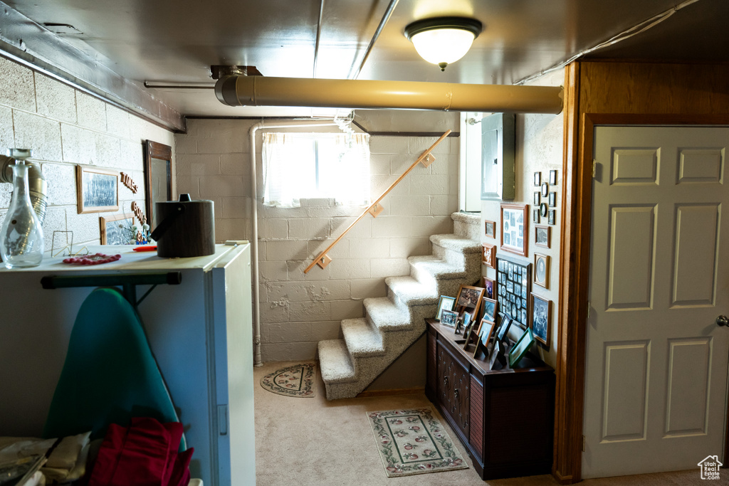Basement featuring stairs, concrete block wall, and carpet floors