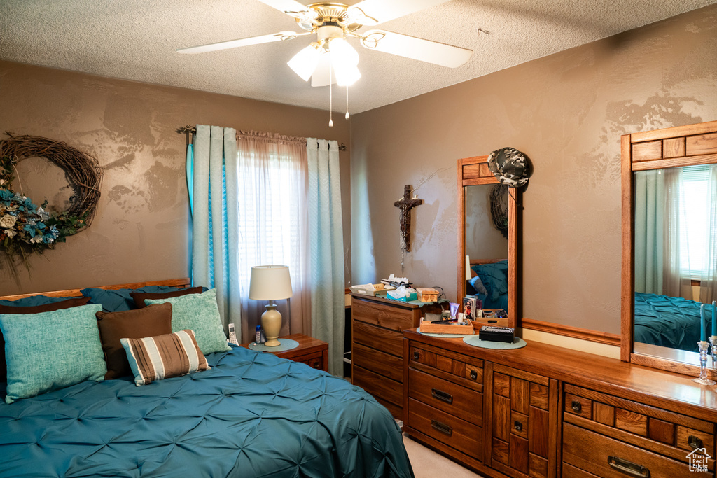 Bedroom featuring multiple windows, a textured ceiling, and a ceiling fan