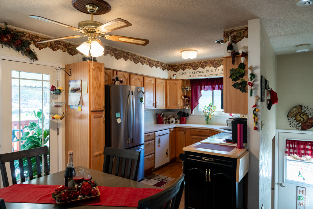 Kitchen with freestanding refrigerator, white dishwasher, light countertops, a textured ceiling, and ceiling fan