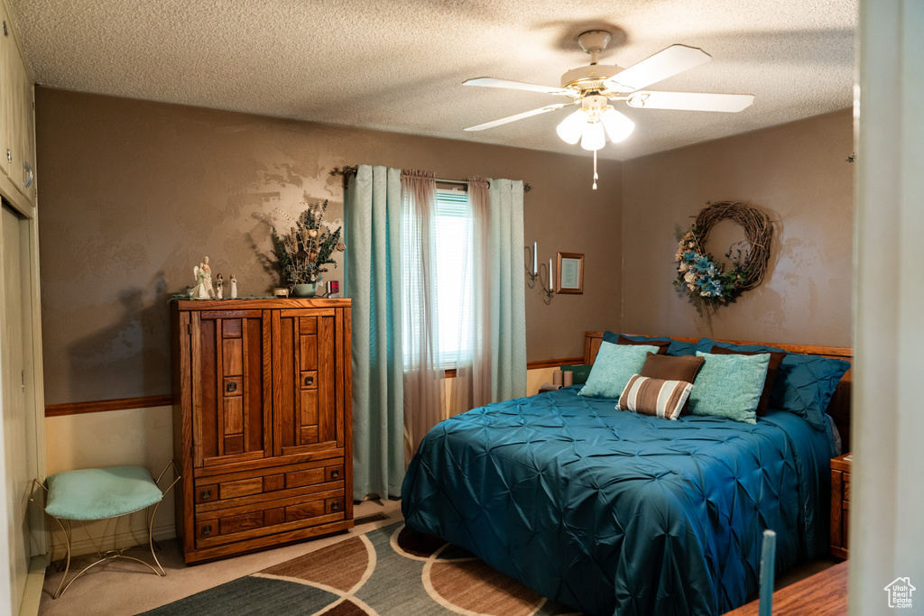Bedroom with a textured ceiling, a ceiling fan, and carpet flooring