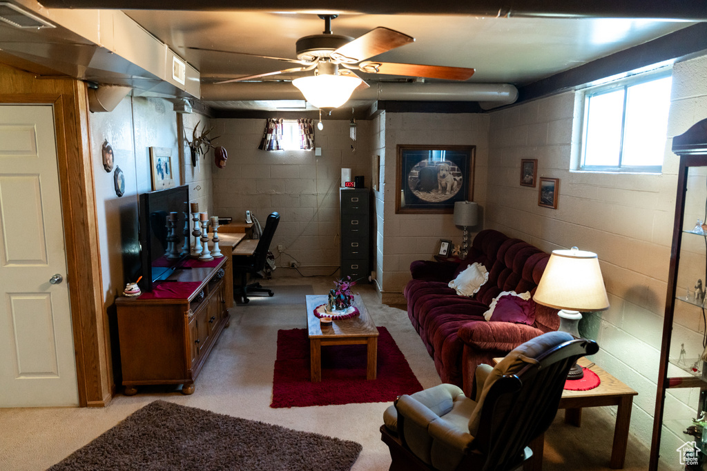Living area featuring concrete block wall and a ceiling fan