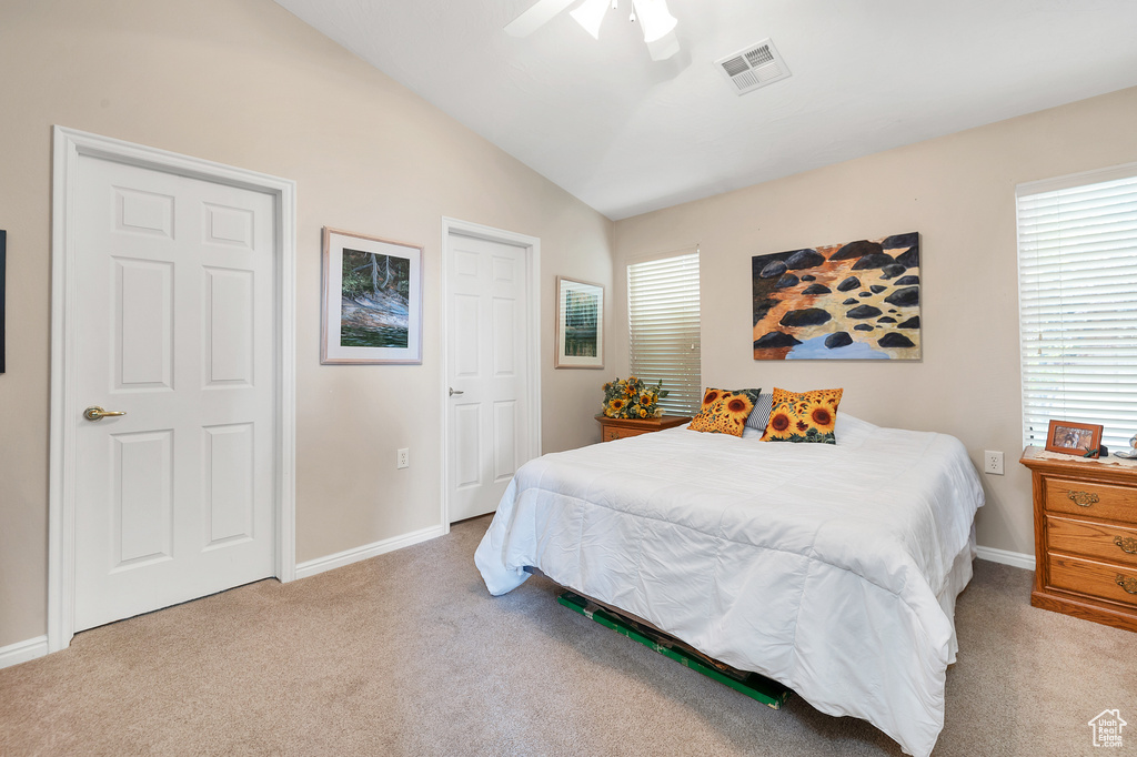 Carpeted bedroom featuring vaulted ceiling, multiple windows, baseboards, and ceiling fan