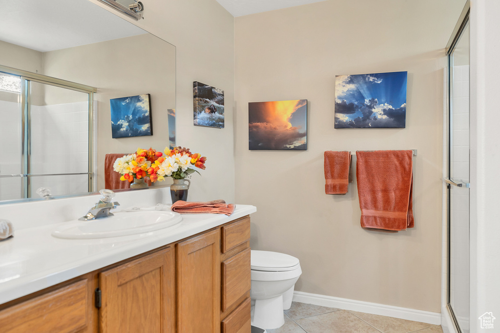 Bathroom featuring tile patterned flooring, a shower with door, toilet, and baseboards