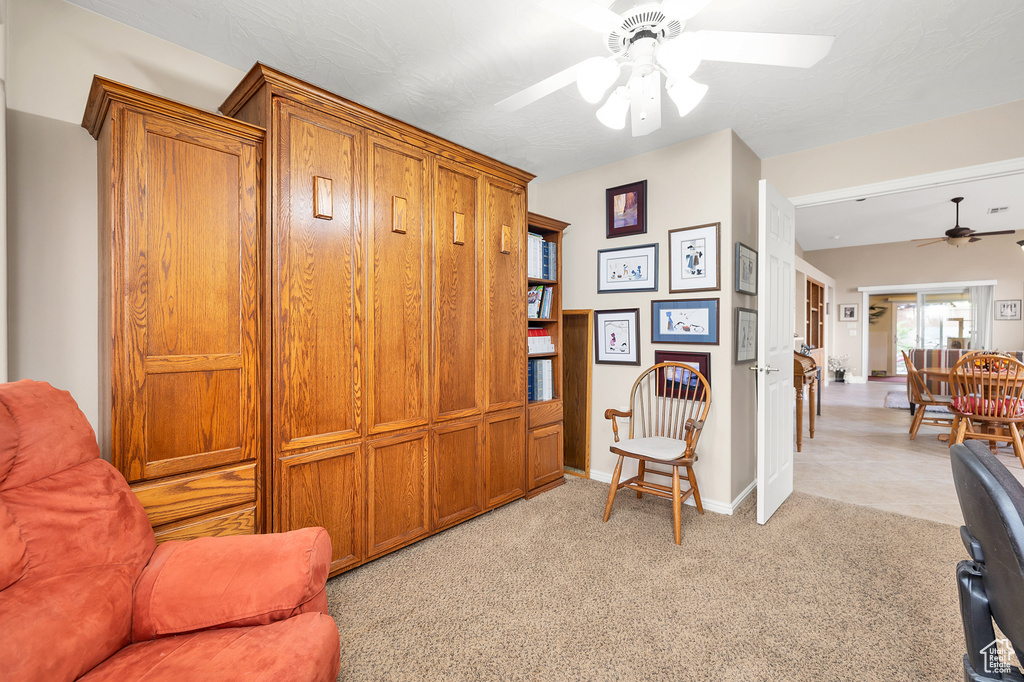 Sitting room featuring a ceiling fan, baseboards, and light carpet