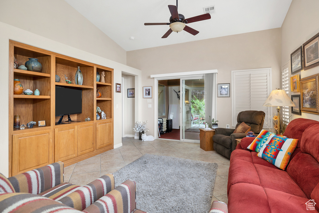 Living area with ceiling fan, vaulted ceiling, light tile patterned floors, and baseboards