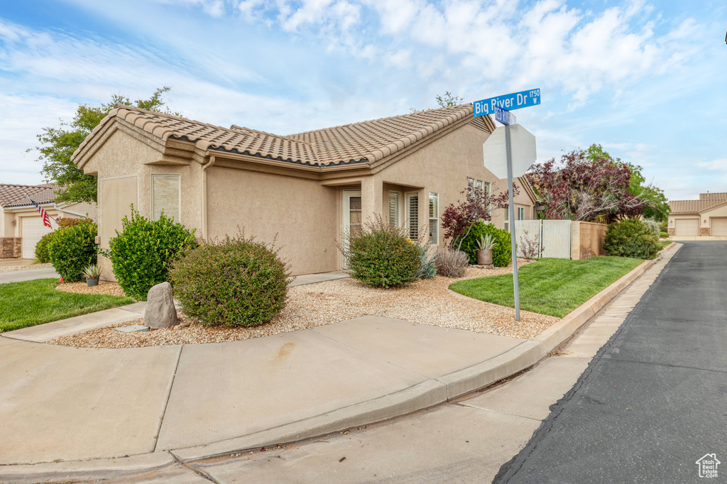 View of property exterior with a tile roof, stucco siding, and fence