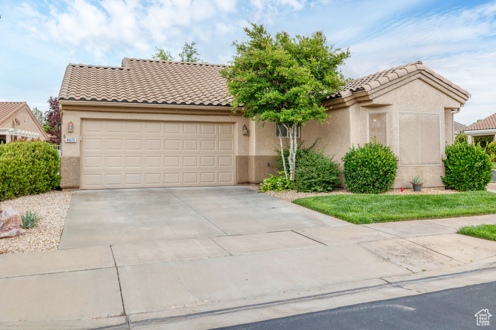 View of front of property featuring driveway, stucco siding, a garage, and a tile roof