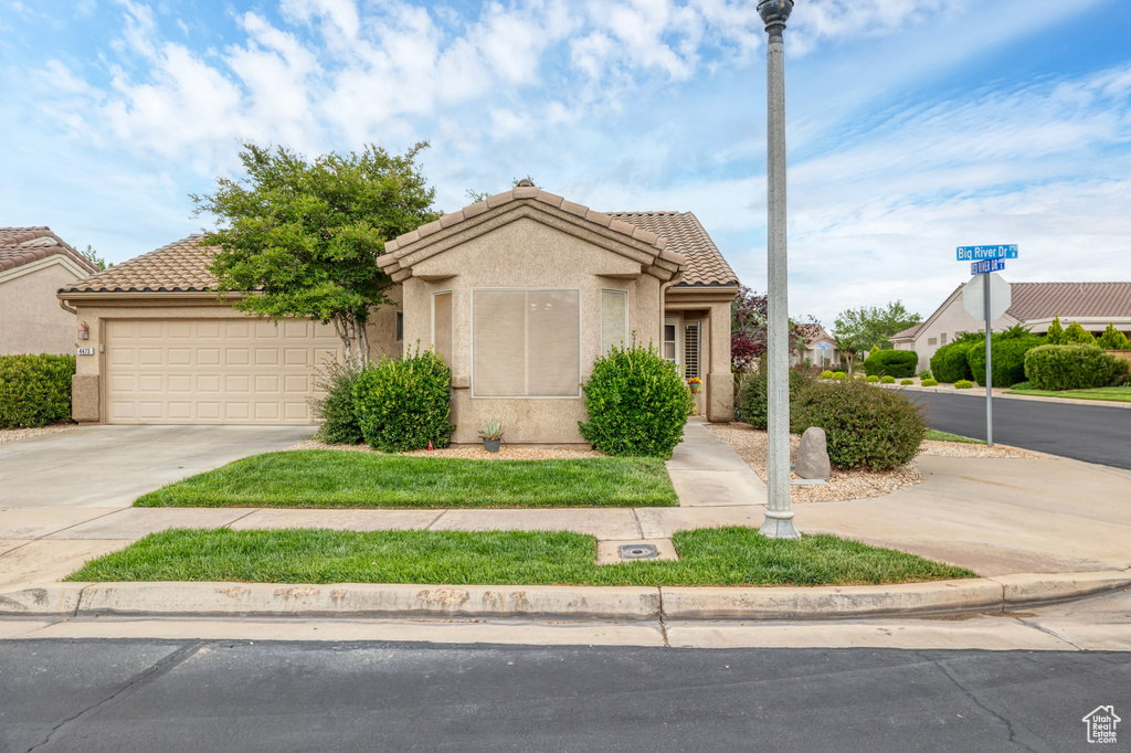 View of front of house with driveway, a garage, a tile roof, and stucco siding