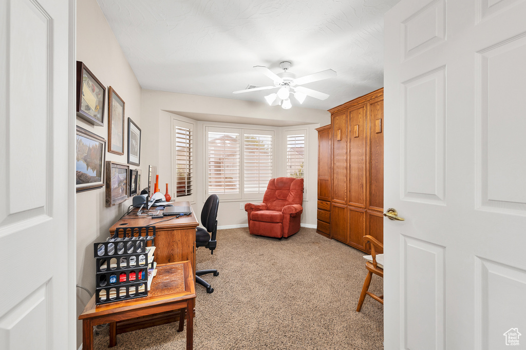 Carpeted home office featuring a ceiling fan and baseboards